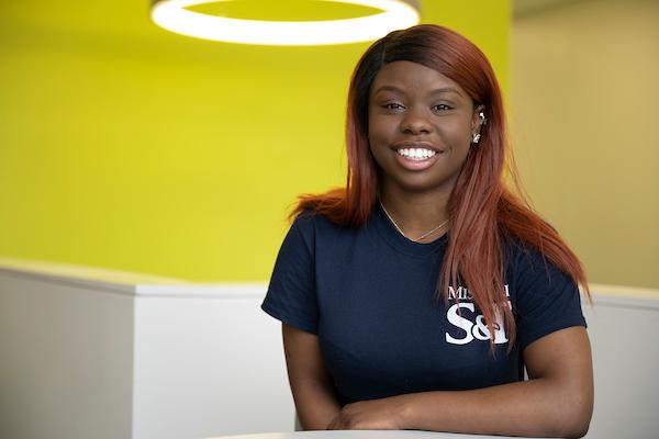 Female student wearing a navy blue t-shirt sits at a table.